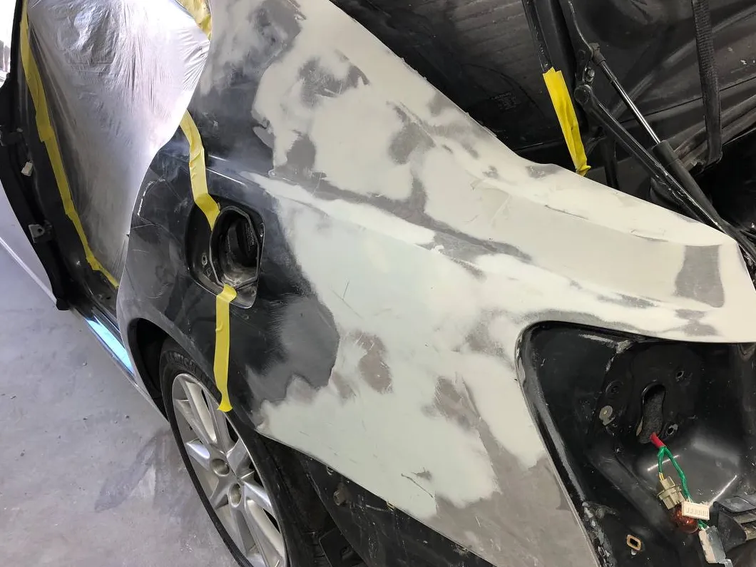Rear quarter panel of a white car in primer during body repair