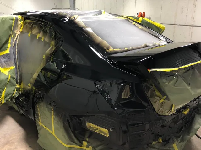 Black sedan with the rear end masked for refinishing