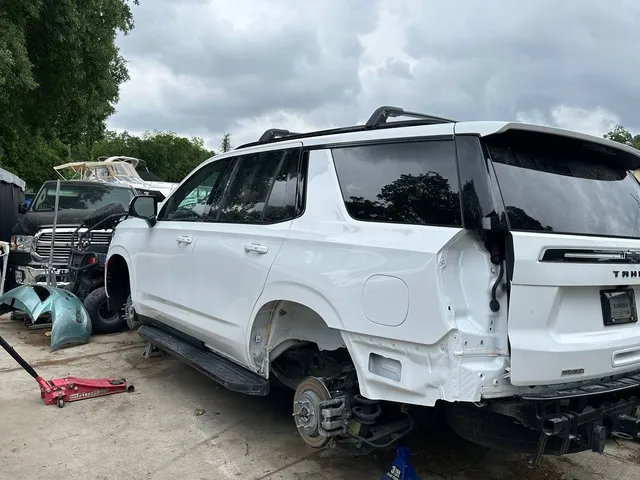 White full-size SUV with rear collision damage before repair