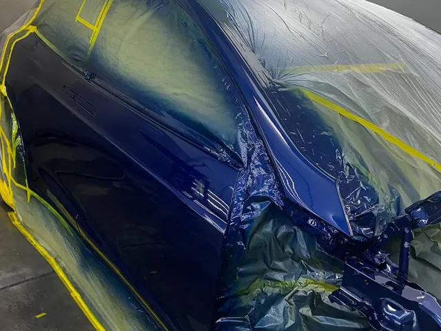 Blue car front end masked for paint after collision repair
