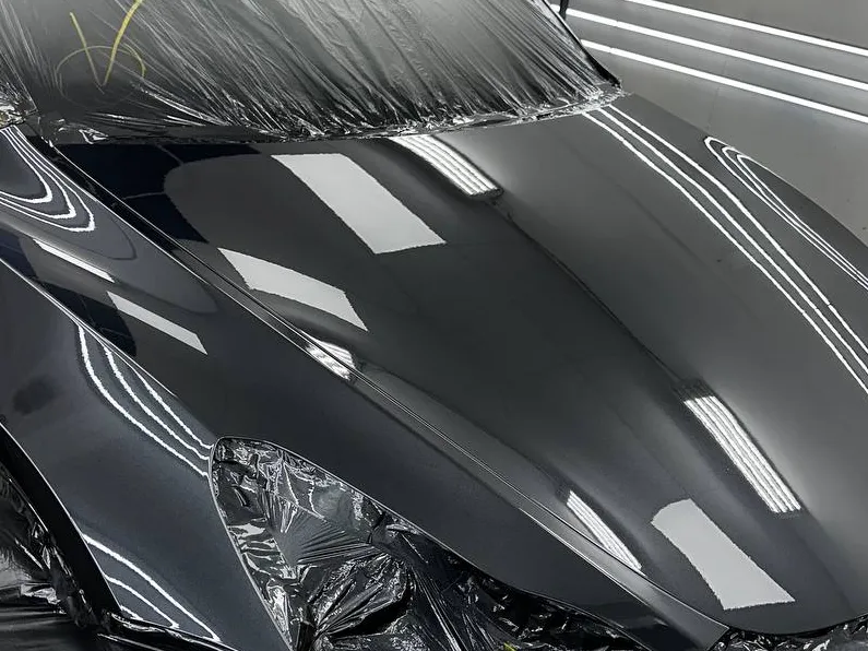 Front end of a black car refinished in the paint booth
