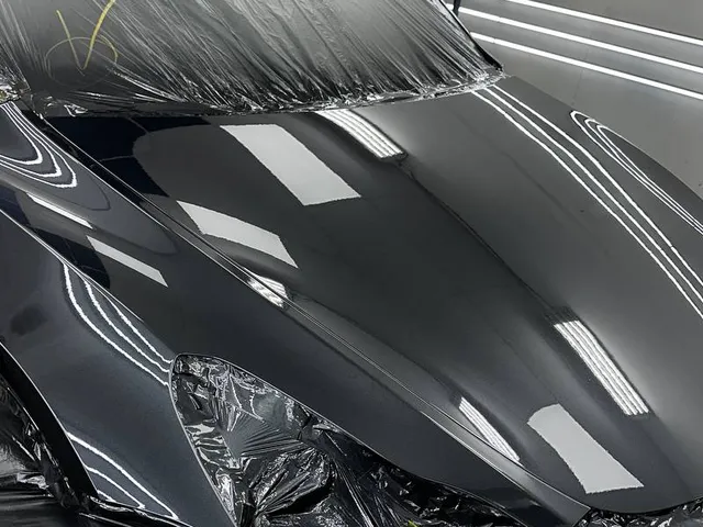 Front end of a black car refinished in the paint booth