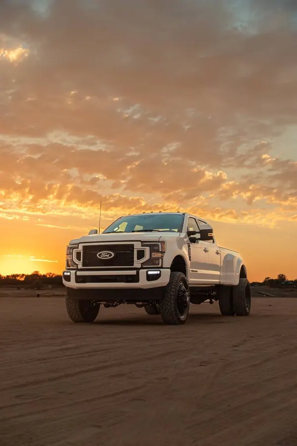 Lifted white Ford Super Duty dually truck at sunset